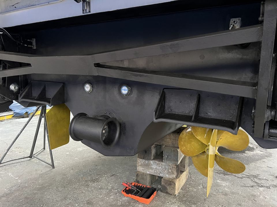 Stern of a boat in the yard with a tool tray on the blocks underneath